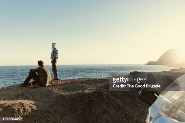 couple looking at sea against clear sky during sunset - mare moto foto e immagini stock