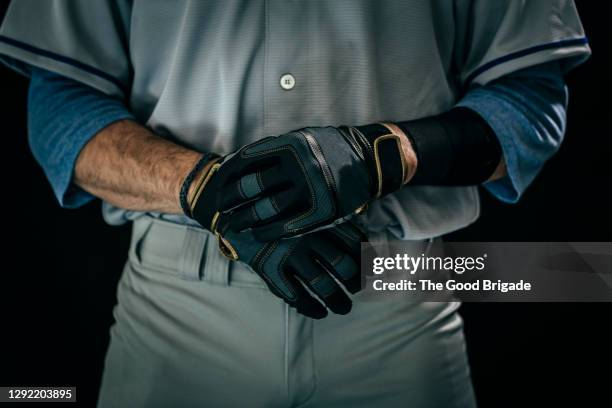 midsection of young male baseball player wearing batting gloves - divisa da baseball foto e immagini stock