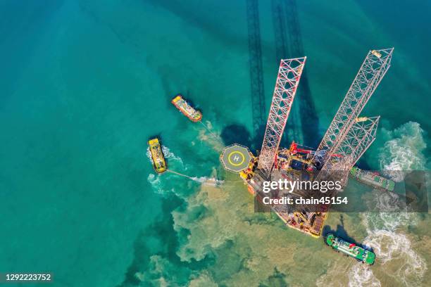 aerial view of drilling oil rig move operation at oil field industry with towing boat from shore in shallow water. - oil field aerial stockfoto's en -beelden