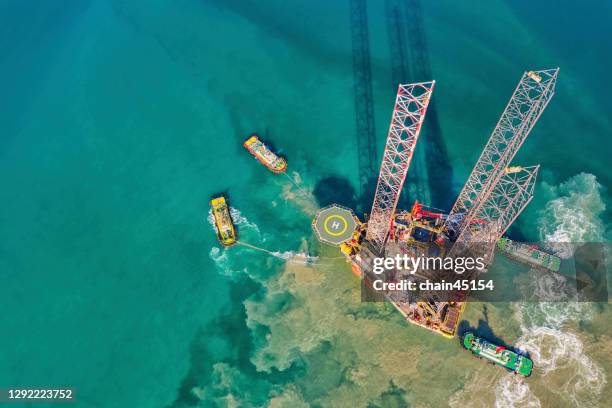 aerial view of drilling oil rig move operation at oil field industry with towing boat from shore in shallow water. - oil field stockfoto's en -beelden