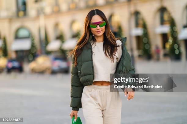 Patricia Gloria Contreras wears neon colored shiny sunglasses from Quay, a green winter bomber puffer jacket from Nastygal, a white cropped top from...