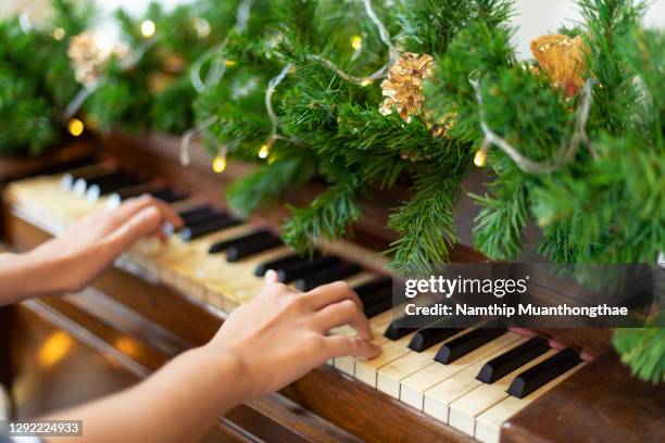 play christmas melody on piano with support of diy christmas tree, merry christmas celebration, happy seasonal holidays. - happy holidays family stock pictures, royalty-free photos & images