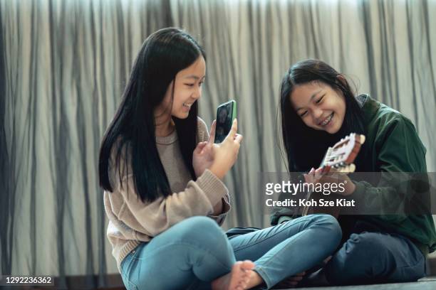 preteen asiatiska systrar gör en enkel liveinspelning av sig själva spela gitarr - girls playing with themselves bildbanksfoton och bilder