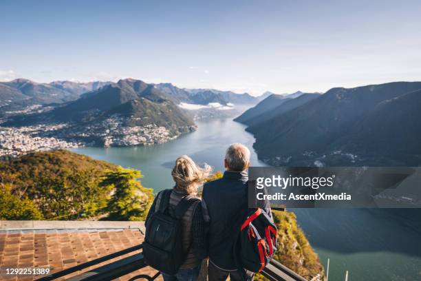 朝の湖ルガーノの上の成熟したカップルのハイキング - travel and not business ストックフォトと画像