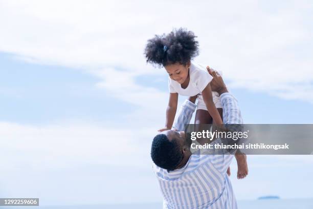 shot of father throwing his little daughter up in the air and playing together in beach with fun and love in summer vacation. - dad throwing kid in air imagens e fotografias de stock