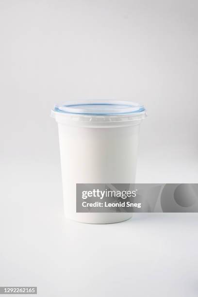 food photography of clean white sterile plastic jar of natural dairy product (sour cream) front view on a light gray background isolated close up - yoghurt lid stock pictures, royalty-free photos & images