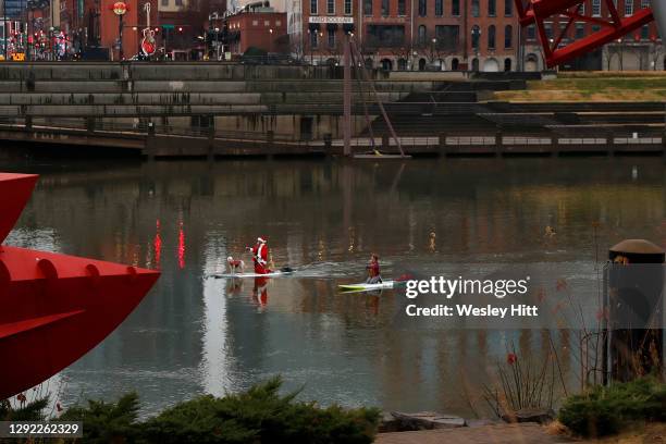 Man dressed as Santa Claus paddleboards on the Cumberland River by downtown Nashville outside of the Nissan Stadium prior to the Detroit Lions and...