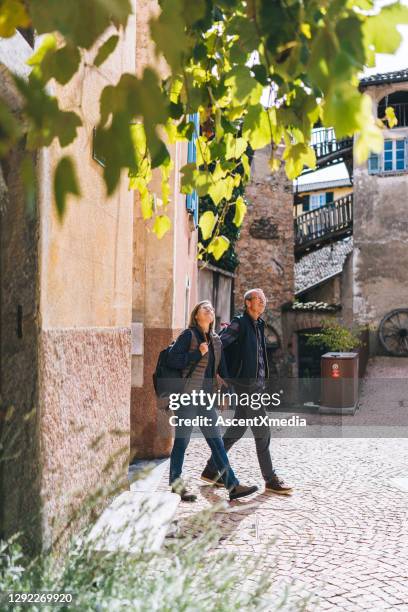 mature couple walk, hand in hand, through sunny european city - lugano switzerland stock pictures, royalty-free photos & images