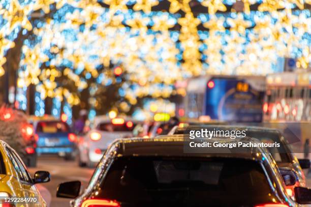 cars and public transportation on an avenue under blurred christmas lights - christmas driving stockfoto's en -beelden