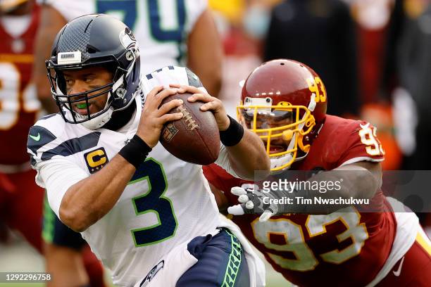 Quarterback Russell Wilson of the Seattle Seahawks eludes the tackle of defensive tackle Jonathan Allen of the Washington Football Team in the second...