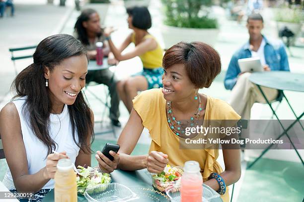 two women friends eating at outdoor cafe - group of friends out to lunch stock pictures, royalty-free photos & images