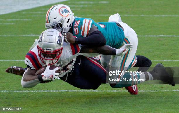 Sony Michel of the New England Patriots is tackled by Jerome Baker of the Miami Dolphins during the fourth quarter in the game at Hard Rock Stadium...