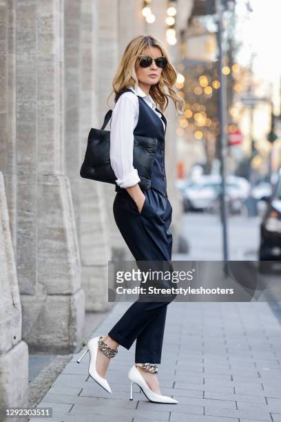 Influencer Gitta Banko wearing dark blue high-rise pants with tapered legs by Nili Lotan, a matching dark blue vest by Nili Lotan, a white blouse by...