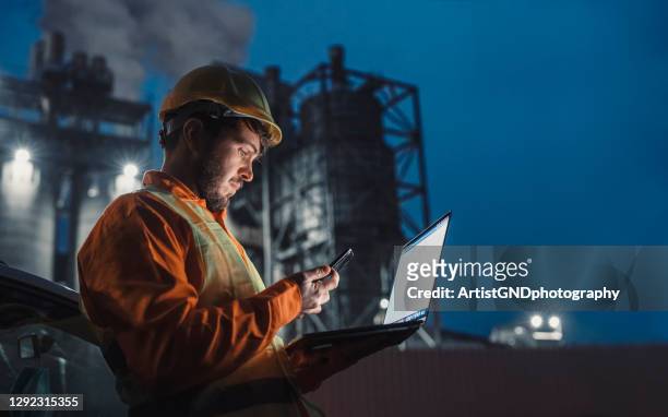 engineer working nightshift and using technology in front of petroleum industrial factory. - crude oil stock pictures, royalty-free photos & images