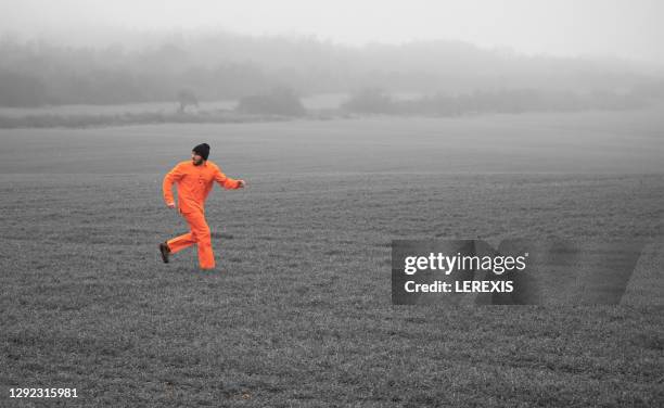 a man escaped from prison running across a deserted field - prison escape stock pictures, royalty-free photos & images