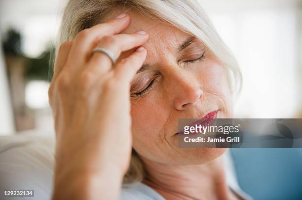 senior woman with headache - headache stock-fotos und bilder