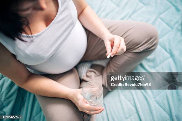 mulher grávida tomando pílula em casa - tomando remédio - fotografias e filmes do acervo