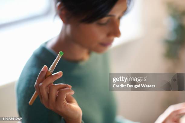 asian artist holding paint brush with green paint, close up. - art studio stock pictures, royalty-free photos & images