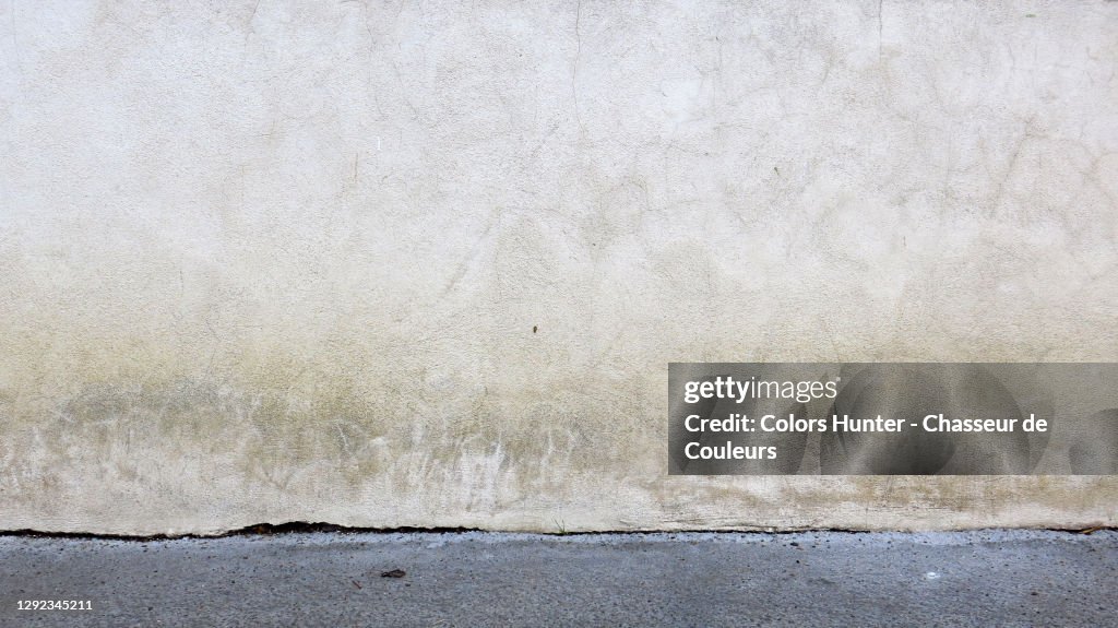 White concrete wall with patina and gray sidewalk in Paris