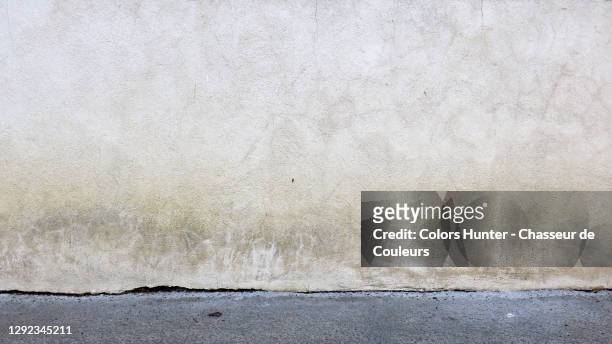 white concrete wall with patina and gray sidewalk in paris - wall building feature stock pictures, royalty-free photos & images