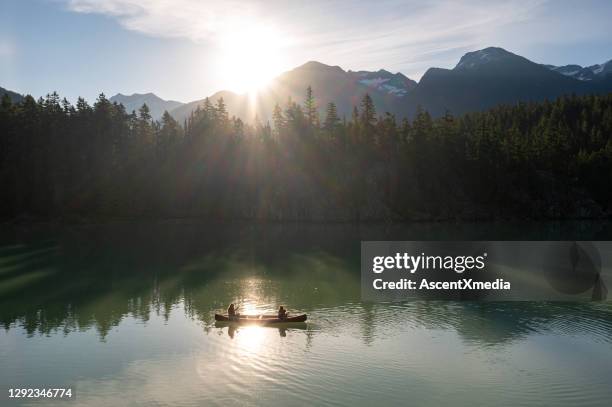 family canoeing on a stunning mountain lake - canoe stock pictures, royalty-free photos & images