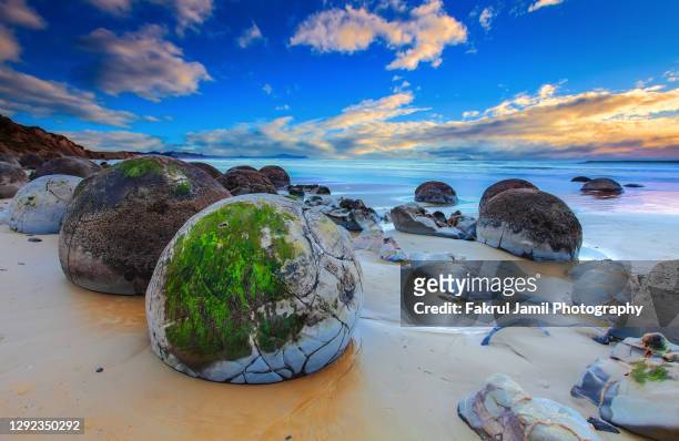 beautiful sunrise at moeraki boulders, new zealand - new zealand beach stock pictures, royalty-free photos & images