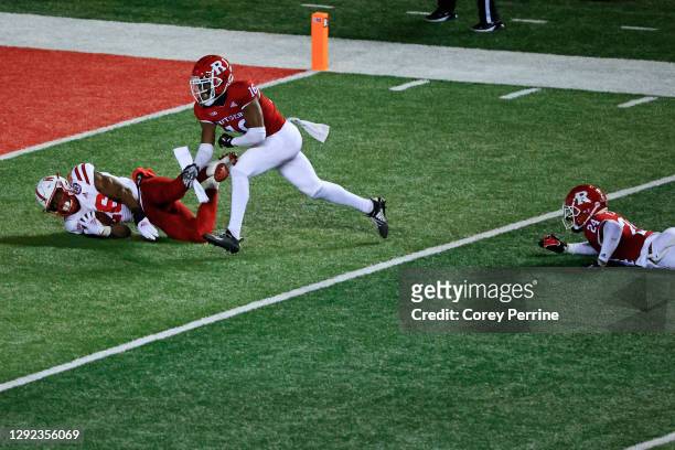 Dedrick Mills of the Nebraska Cornhuskers is tripped up by Naijee Jones of the Rutgers Scarlet Knights as Max Melton helps during the second quarter...