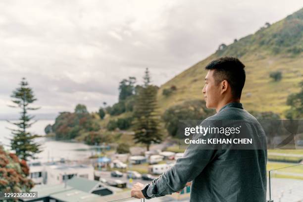 young asian man relaxing, take it easy in standing on hotel balcony and enjoy the landscape - looking over balcony stock pictures, royalty-free photos & images