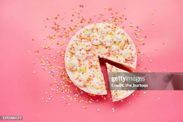 high angle view of cream cake and colourful sugar sprinkles on pink background - espolvorear fotografías e imágenes de stock