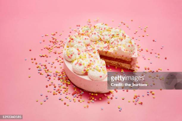 high angle view of cream cake and colourful sugar sprinkles on pink background - sprinkles stock-fotos und bilder