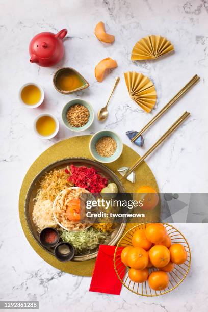 chinese new year food, raw fish salad “yusheng” and other traditional food and drinks on marble table top flat lay image. - marble table top view stock pictures, royalty-free photos & images