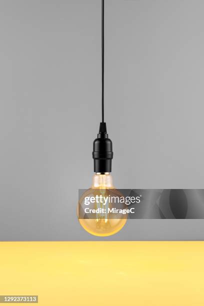 retro style light bulb on yellow and gray - hanging lamp stock pictures, royalty-free photos & images