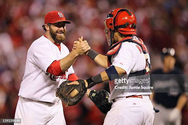 Jason Motte and Yadier Molina of the St. Louis Cardinals celebrate after they won 7-1 against the Milwaukee Brewers during Game Five of the National...