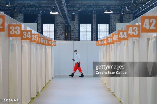Worker from the German Red Cross walks among inoculation cabins at the completed Covid-19 vaccination center at the Arena Berlin events venue on...