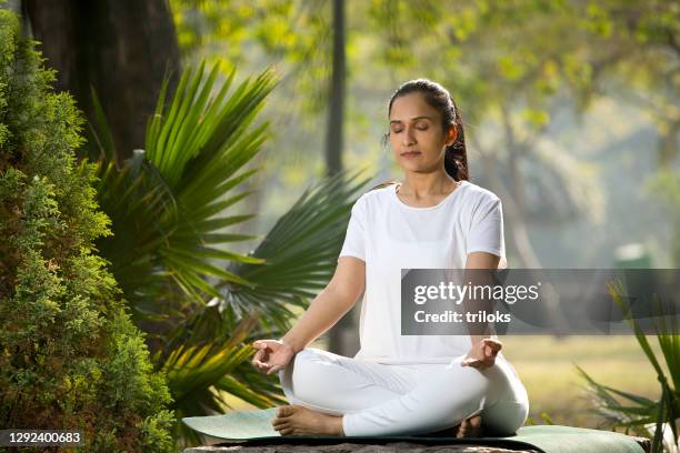 woman meditating at park - yoga day stock pictures, royalty-free photos & images