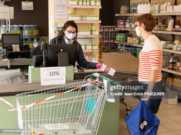 Cliente et caissière portant des masques dans le magasin de distribution alimentaire "La Vie Claire" le 27 avril 2020, La-Frette-sur-Seine, France.