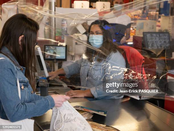 Caissière avec un masque, protégée derrière un film plastique et cliente portant un masque dans un magasin de distribution alimentaire "U" le 27...