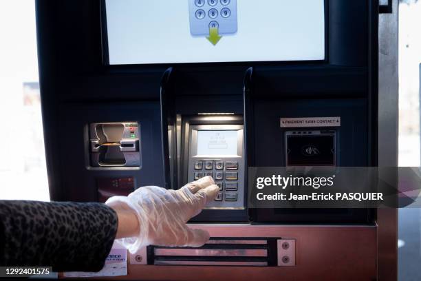 Main gantée effectuant un code de carte bleue à une borne de paiement au Chronodrive, 25 mars 2020, La-Frette-sur-Seine, France