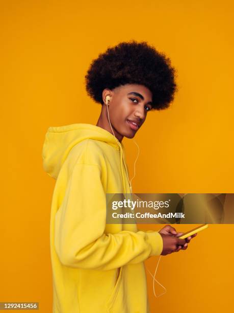 african american man with african hairstyle wearing hoodie standing over isolated yellow background - mens hair model stock pictures, royalty-free photos & images