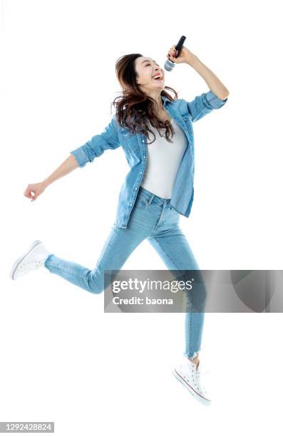 gelukkige vrouw die en op witte achtergrond zingt en springt - microphone white background stockfoto's en -beelden