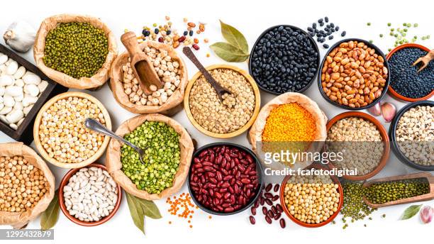 large variety of dried beans, legumes and cereals shot from above on white background - bean stock pictures, royalty-free photos & images