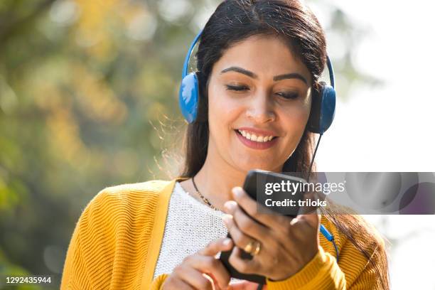 使用手機和耳機聽音樂的女人 - indian music 個照片及圖片檔