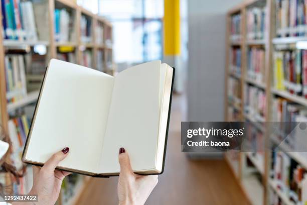 mano donna che tiene in mano un libro vuoto in biblioteca - chinese dictionary foto e immagini stock