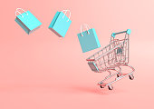 Flying shopping cart with shopping bags on a pink background