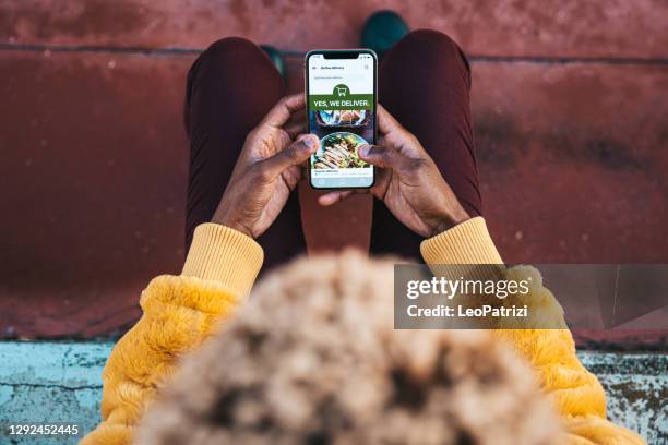 vrouw die voedsel door leverings mobiele app bestelt - on demand stockfoto's en -beelden