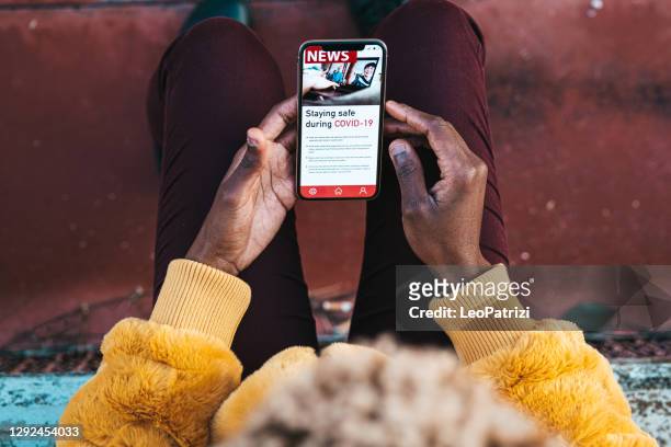 woman reading news about covid on mobile phone - the media stock pictures, royalty-free photos & images