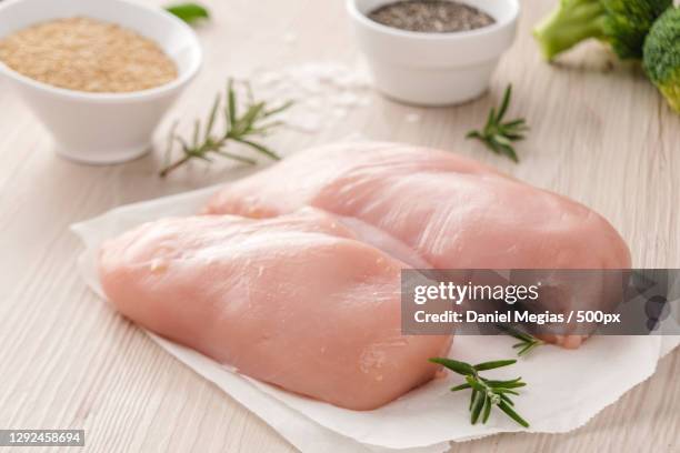 high angle view of raw meat with herbs on table - hühnchenbrust stock-fotos und bilder