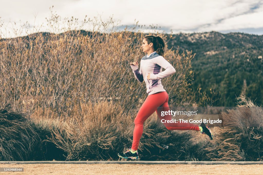 Side view of female athlete running by field