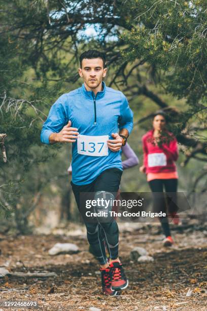 confident young male athlete running in forest during race - bib stock pictures, royalty-free photos & images