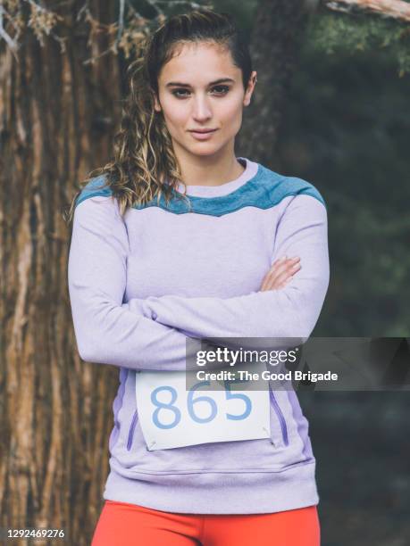 portrait of confident woman standing with arms crossed in forest - bib stock pictures, royalty-free photos & images